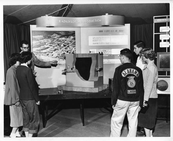 Students gathered in front of a model atomic pile at the Atomic Energy Exhibit