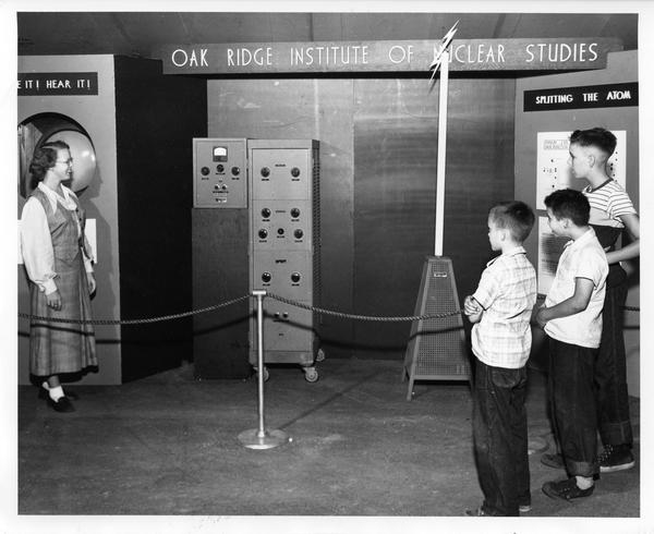 Students look on as an exhibit demonstrator explains equipment at the traveling Atomic Energy Exhibit