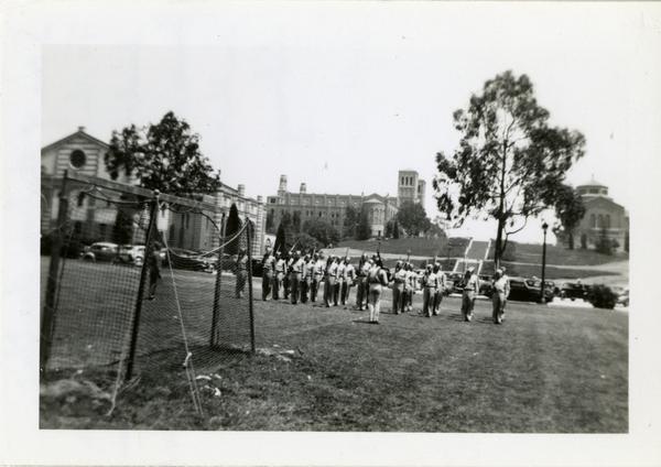 Drill team practicing on soccer field with Janss Steps leading up to Kaufman Hall, Royce Hall and Powell Library in the background, June 1943