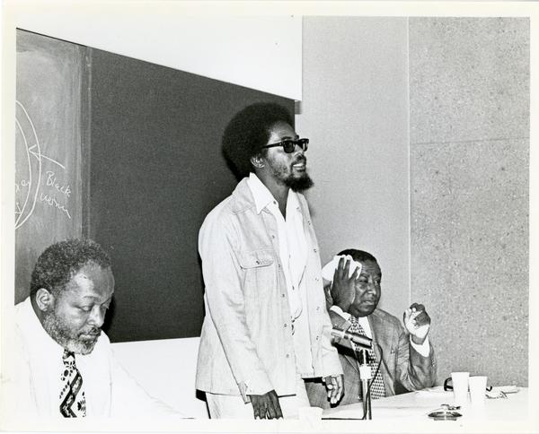 Man standing up among a panel of speakers at the Center for African American Studies