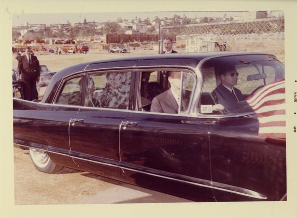 President Johnson in a limousine with guards around the vehicle, charter day 1964