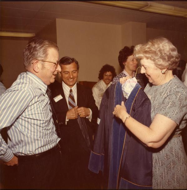 President Hitch being assisted with his robes by Patty Carver and Paul Christopolos, Charter Day 1975