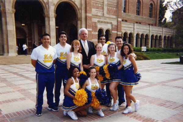 UCLA cheerleaders pose with unidentified man in front of Royce Hall