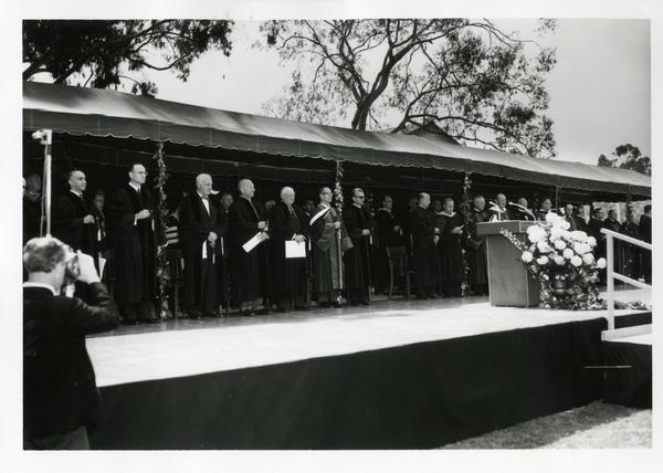 Faculty and speakers standing up on stage at Commencement, 1964