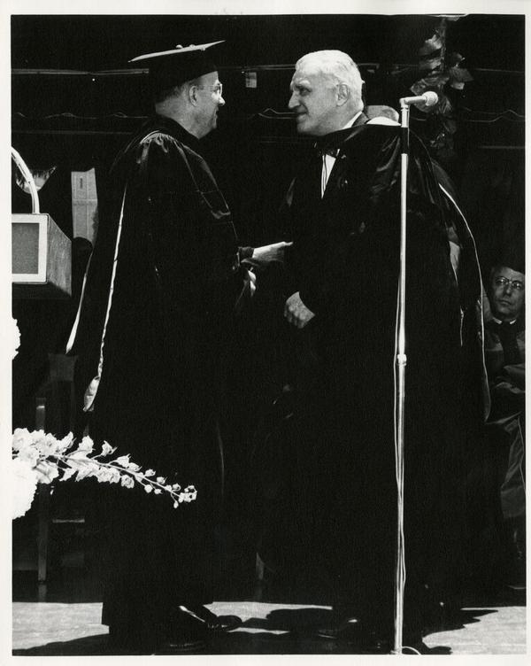 President Clark Kerr shaking hands with a unidentified man at Commencement, 1964