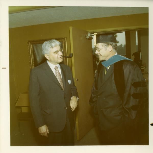 Commencement participant talks with man with a pipe, June 17, 1970