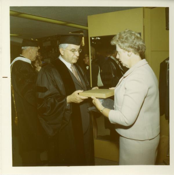 Commencement participant is handed a package by a woman, June 17, 1970