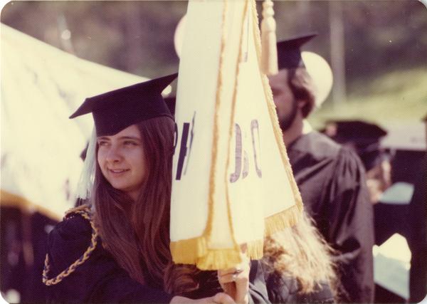 Student holding a UCLA flag at commencement, 1976