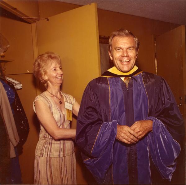 UCLA Alumni President James Collins in the robing room being assisted with his robe, June 1976