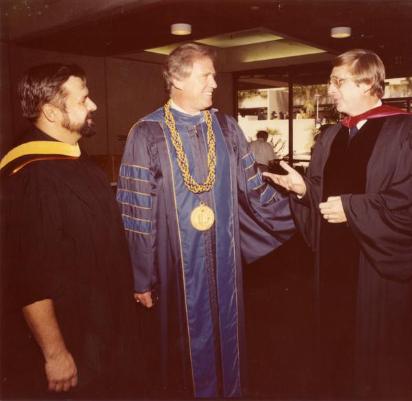 Chancellor Charles E. Young talking with two unidentified men at commencement, June 1979