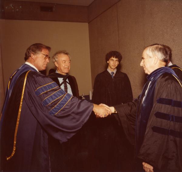 Two members of the party platform shake hands at commencement, June 1979