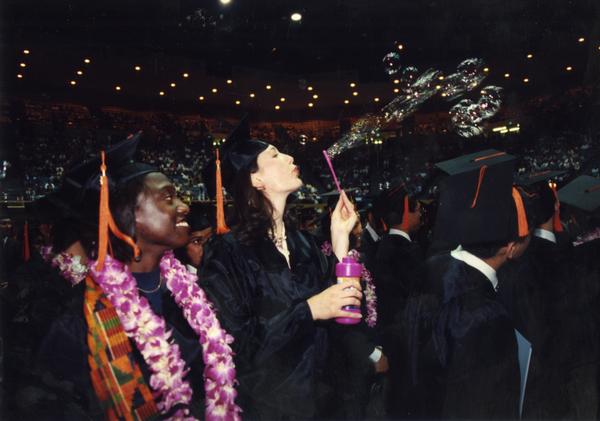 Graduate blows bubbles at commencement, ca. 1990's