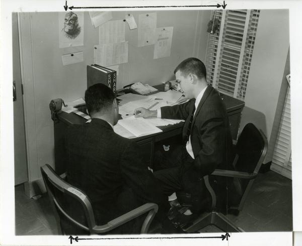Two individuals looking over notes at the Western Data Processing Center