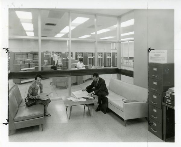 Two individuals sit on couches, reviewing notes at the Western Data Processing Center