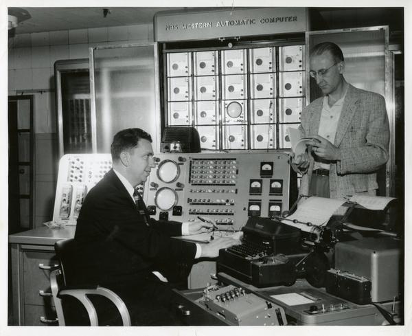 Two workers at equipment desks at the Western Data Processing Center
