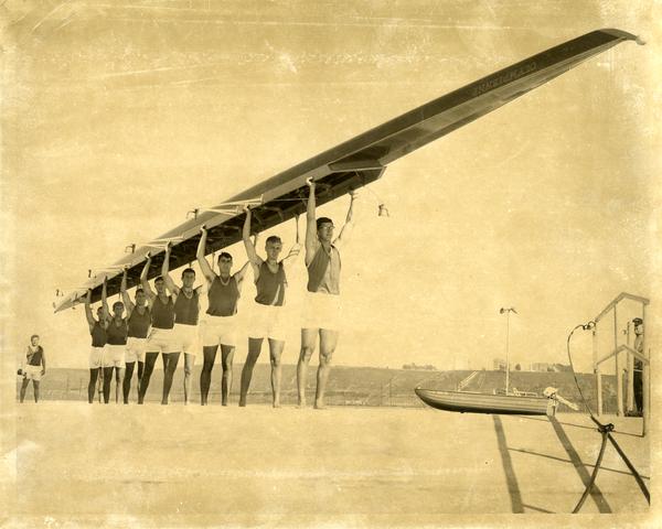 Members of the Varsity Crew team holding up their shell, 1968