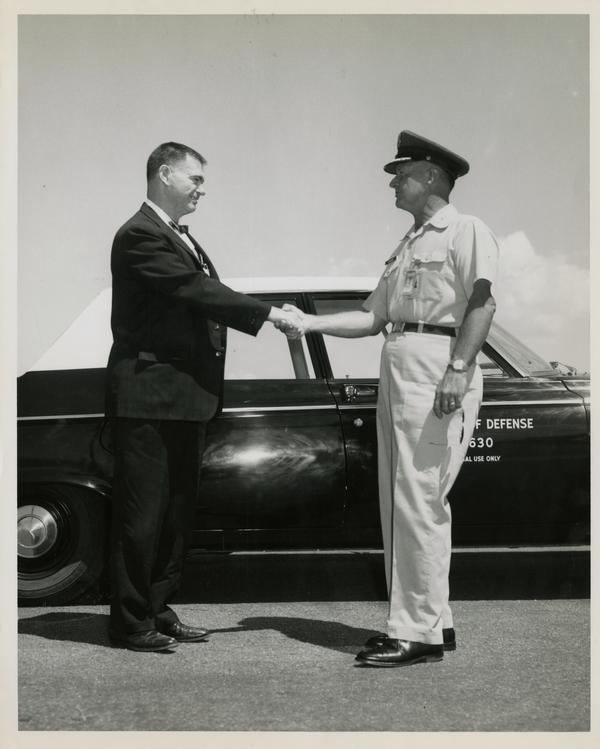 Two attendees, William G. McMillan standing left, of the Defense Science Seminar shaking hands, ca. 1965