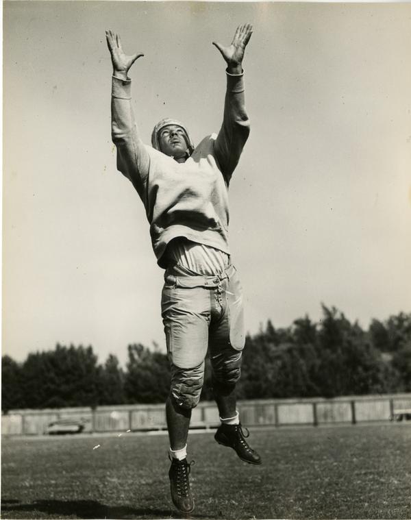 UCLA football player James Millette reaching for a football, 1947