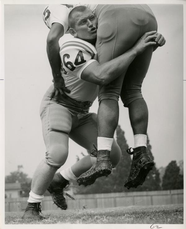 UCLA left guard and right linebacker John Walker tackling a player in practice, 1963