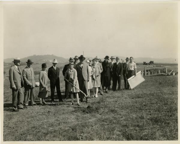 Child with shovel breaks ground for first buiding at new campus groundbreaking ceremony, October 1926