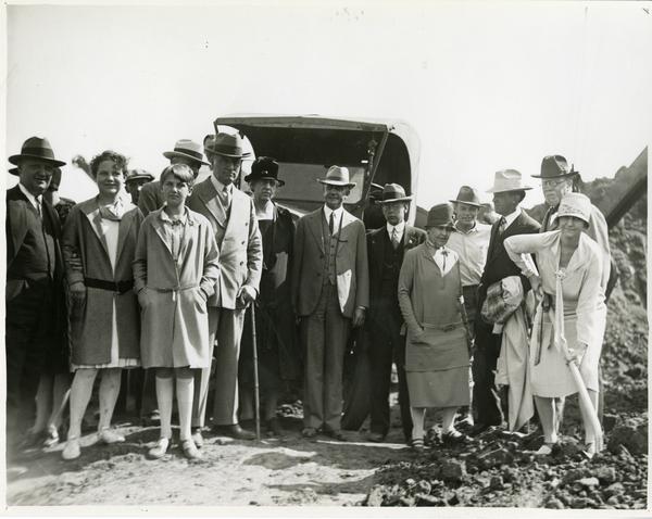 Woman with shovel poses with group at new campus groundbreaking ceremony, October 1926