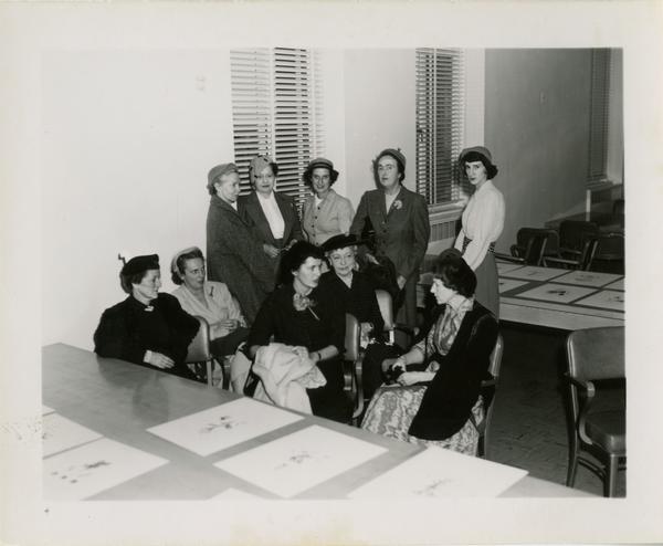Members of the Friends of the UCLA Library group seated and standing around table