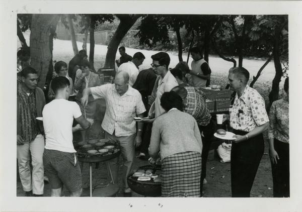 Man serving up hamburgers to students at the geography department picnic