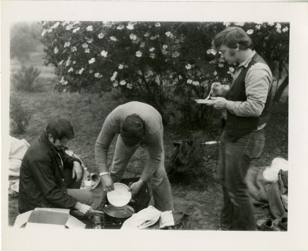 Men of the geography department preparing food on a portable stove