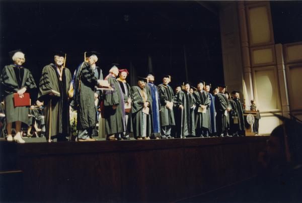 The Emeriti from 1937-1938 Faculty and ceremonial escorts standing on stage during PhD Hooding Ceremony, June 1990