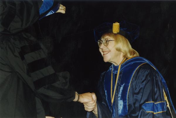 Victoria Fromkin shaking hands with graduate, June 1989
