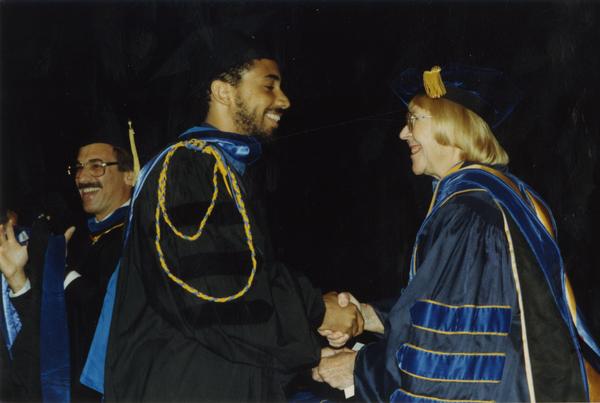 Robin Kelley shakes hands with Victoria Fromkin with Edward Alpers stands in the background during Hooding ceremony, June 1988
