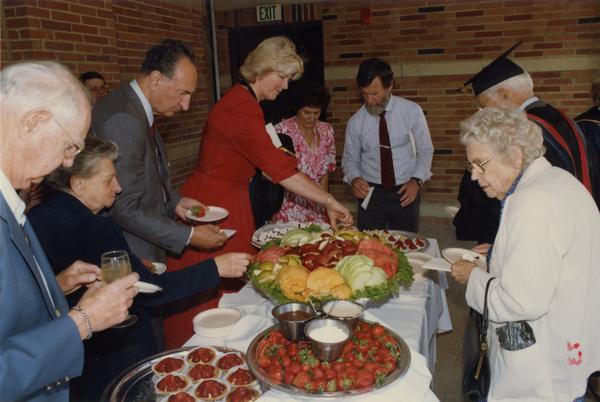 Thomas Jacobs and Mrs Francis Black stand with others around buffee table, June 1988