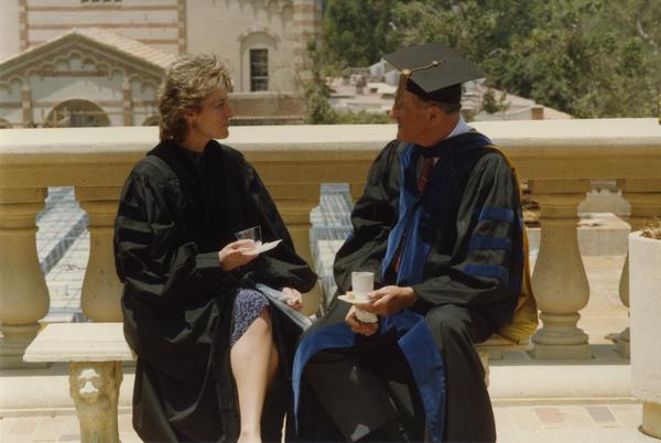 Couple sits on bench beside Royce Hall with Kaufman Hall in the background, June 1988