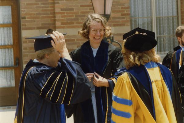 Three Faculty members stand outside Royce Hall during gathering for PhD Hooding Ceremony, June 1988