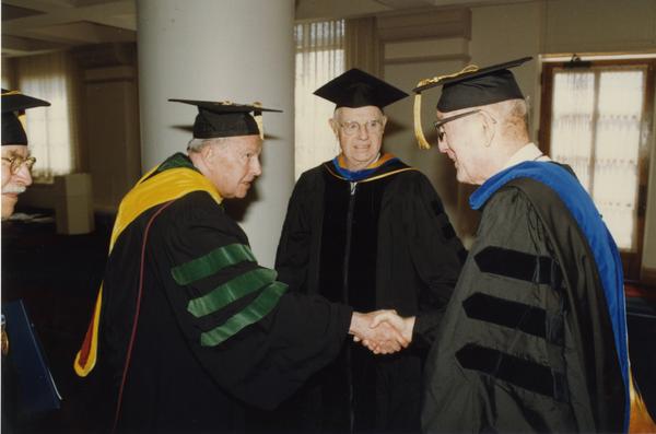 Franklin Murphy and Thomas Jacobs with unidentified man prepare to line up for PhD Hooding Ceremony, June 1988