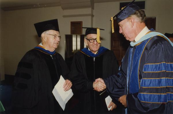 Thomas Jacobs, Elwin Svenson and unidentified man chat before lining up for PhD Hooding Ceremony, June 1988