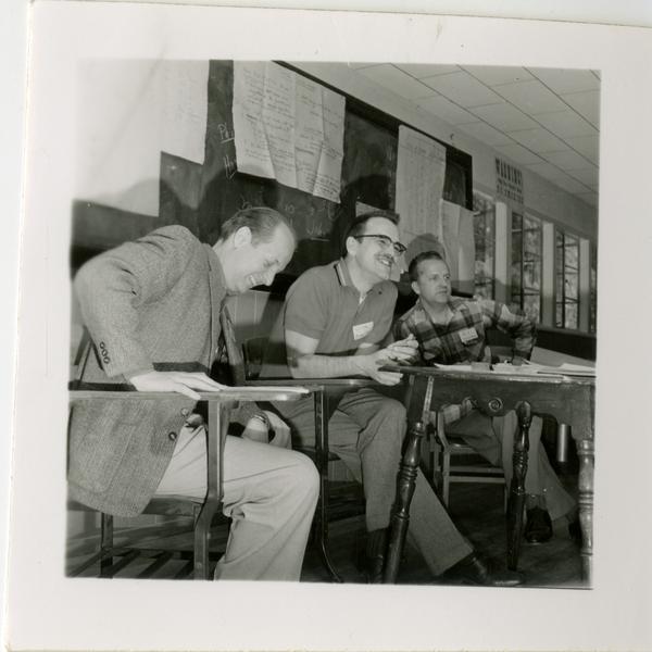 Three men sit at desks inside Lake Arrowhead Lodge, March 1959