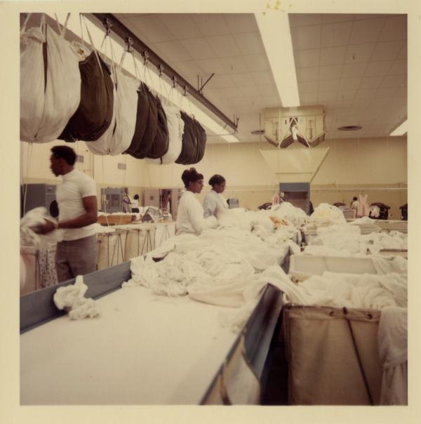 Three laundry workers sort at UCLA Laundry Facility