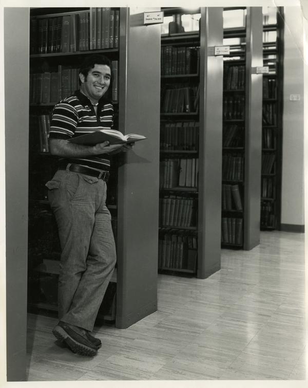 Man reading book in Biomedical Library, ca. 1980