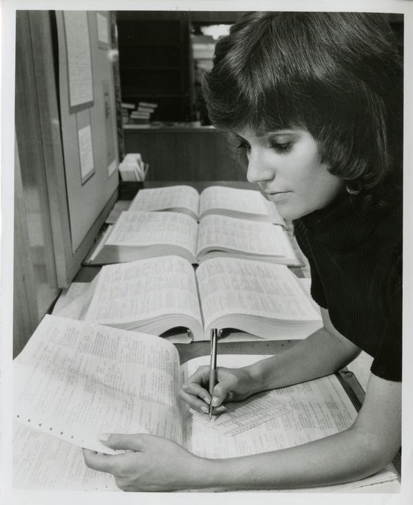 A clerk in the UCLA Biomedical Library checks on a periodical in one of the reference volumes