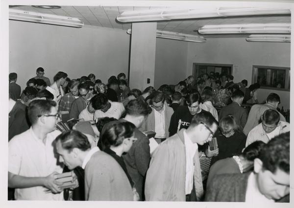 Crowd searching through books at 1962 sale of library duplicates