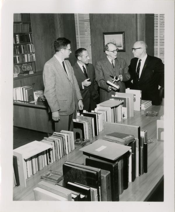 Group of men looking at books, ca. 1953