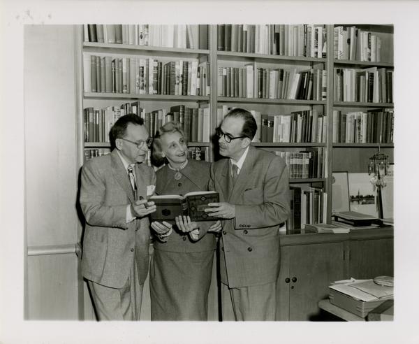 Lawrence Clark Powell holding book with colleagues