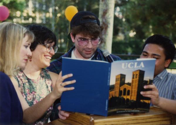 Library staff members looking through UCLA anthology at retirees party, ca. 1991