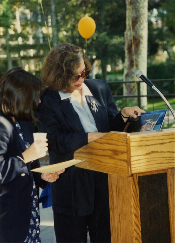 Speaker at the podium confers with another library staff member at a staff event, ca. 1991