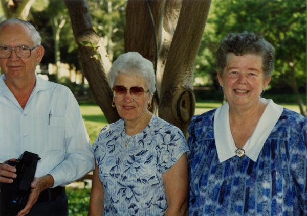 Three library staff members pose for a photo at a staff retirement party, 1991