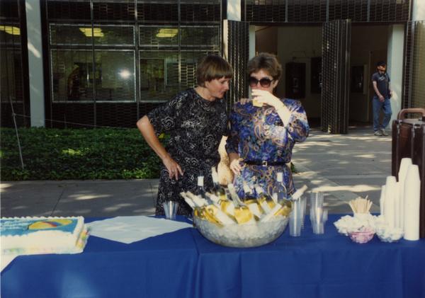Library staff members gather around the wine table at the staff retirement party, 1991