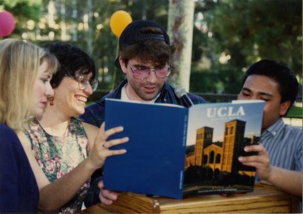 Library staff look through a UCLA book at the staff retirement party, 1991
