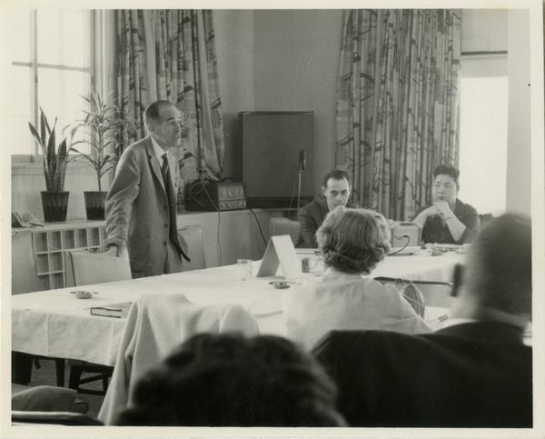 Former university librarian Lawrence Clark Powell addresses a seated crowd on a trip to Japan, ca. 1960