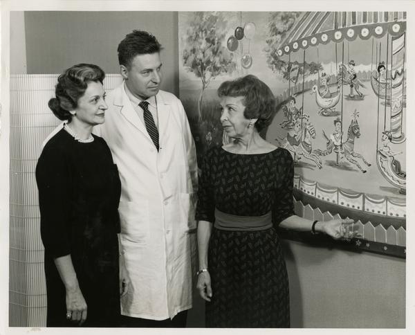 Mrs. Maurice Foonberg, Dr. Norman Q. Brill and Elsa Wein discuss new mural in Institute's children's waiting room, January 9, 1962